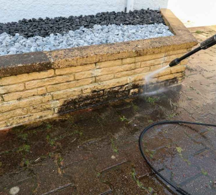 man cleaning wall with high pressure cleaner in close up