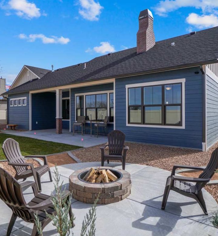 Firepit with stone surround on a concrete patio at the backyard of a blue house